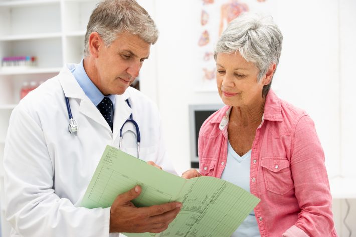 A senior woman and her doctor reviewing what her Medicare plan covers.