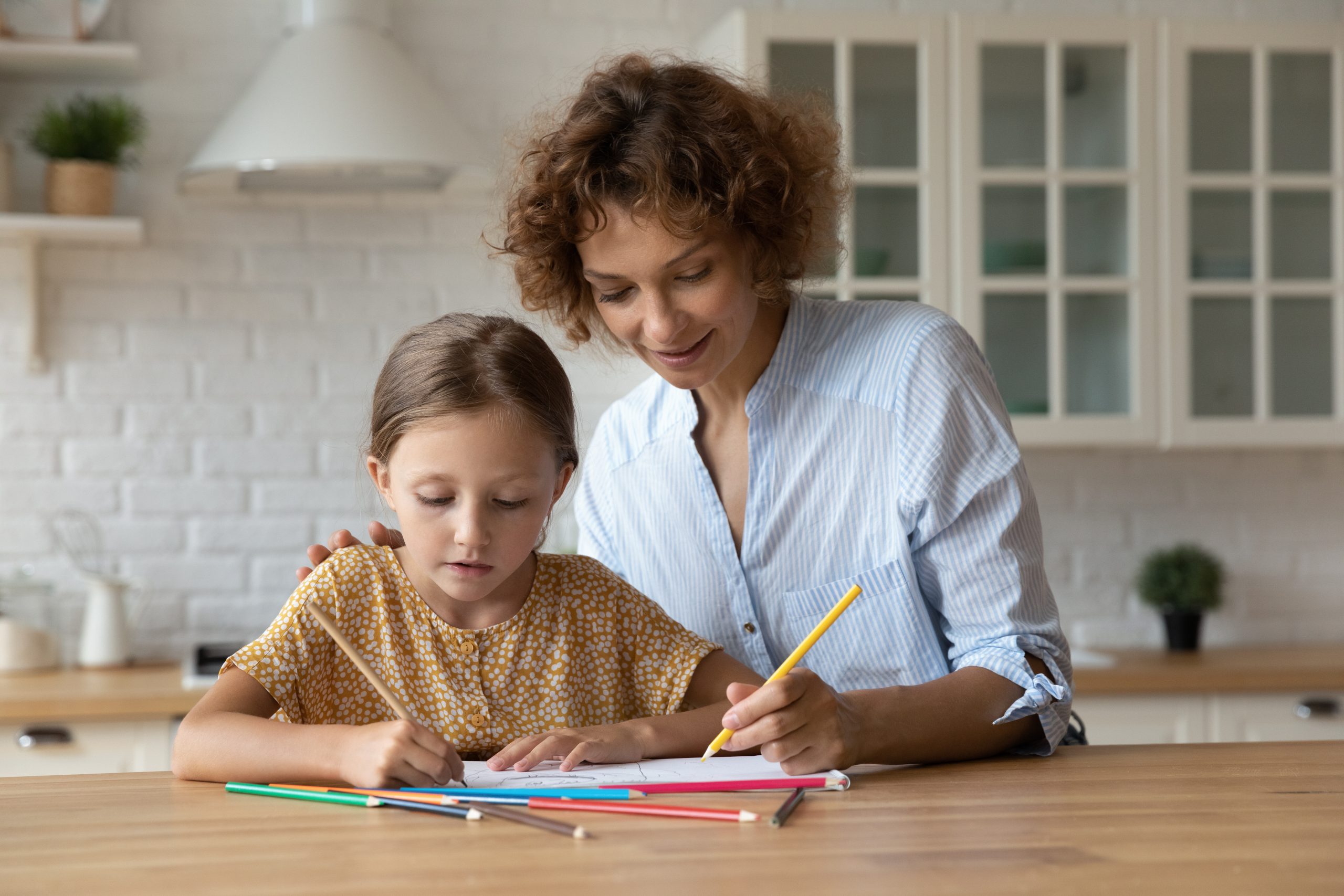Caring Millennial Nanny Help Child To Draw Picture In Album
