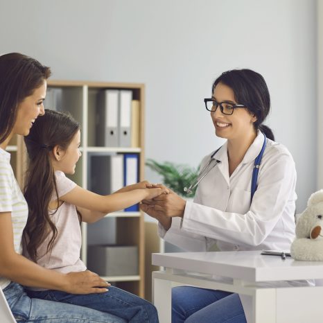Mother and child at the doctor’s office for a preventive care appointment, covered by their health insurance plan as one of the essential health benefits.