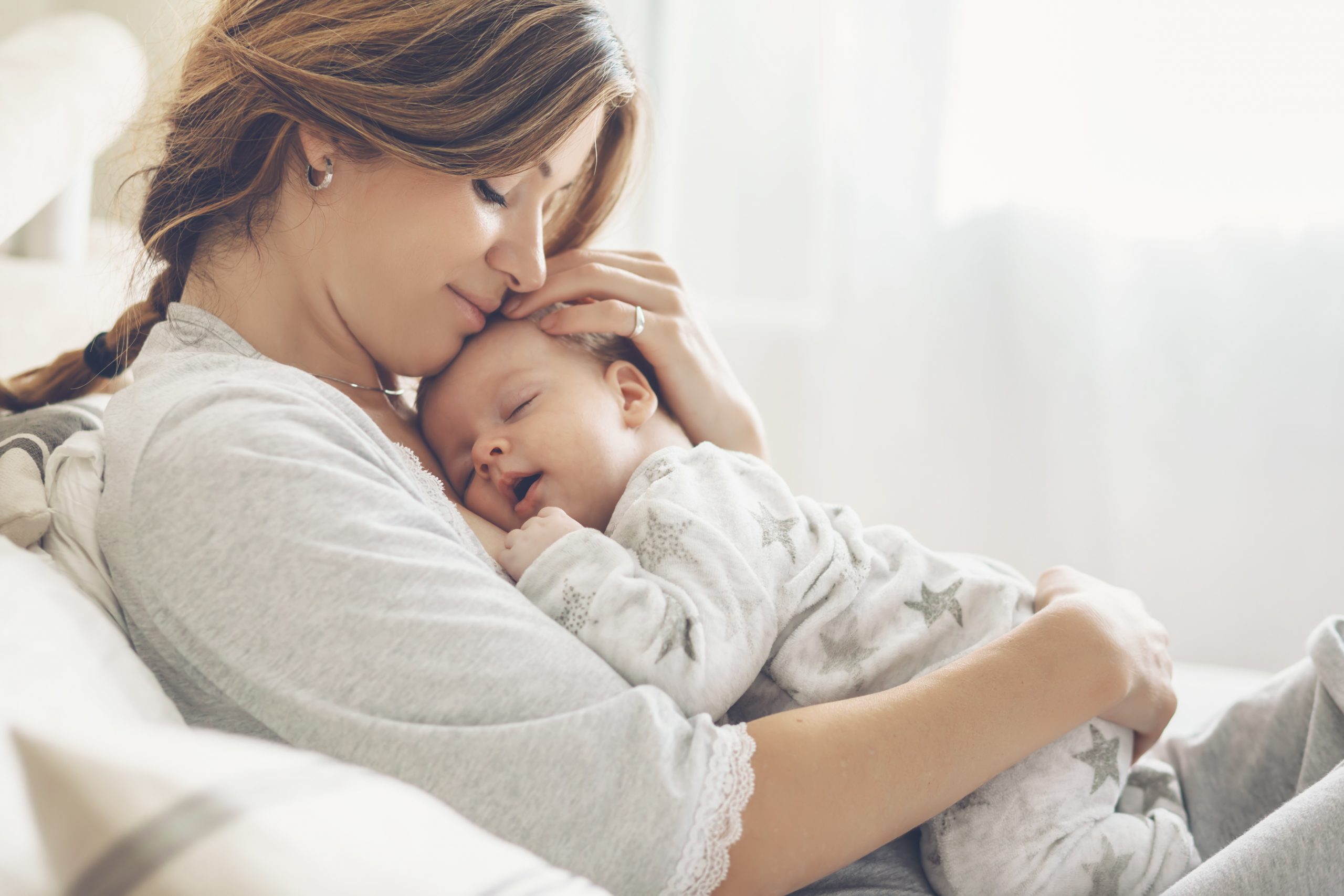 Loving mom carying of her newborn baby at home. Bright portrait