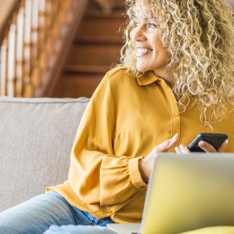 A blonde haired woman smiling and looking at her phone.
