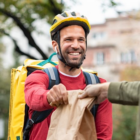 Delivery man giving package to customer. Smiling food delivery c