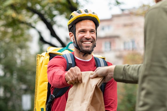 Delivery man giving package to customer. Smiling food delivery c