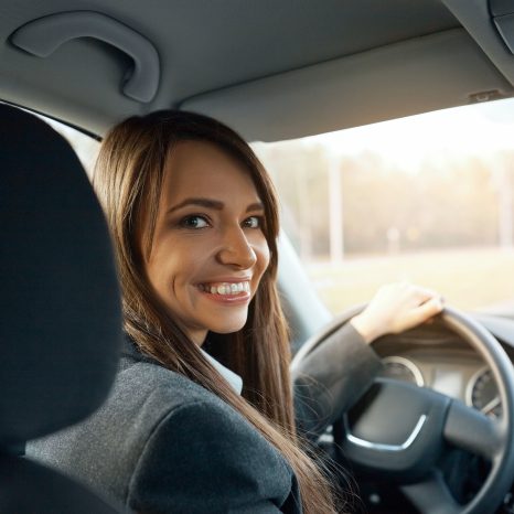 Driver Turns To Passenger Seat And Smiles At Camera. Happy Woman