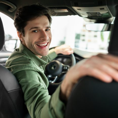 Cheerful Young Man Driving New Automobile After Purchase, Sittin