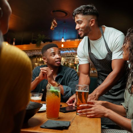 Diverse Group Of Friends Out For Dinner Being Served By Waiter