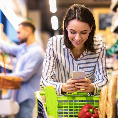 Smiling Female Customer Doing Grocery Shopping Using Smartphone