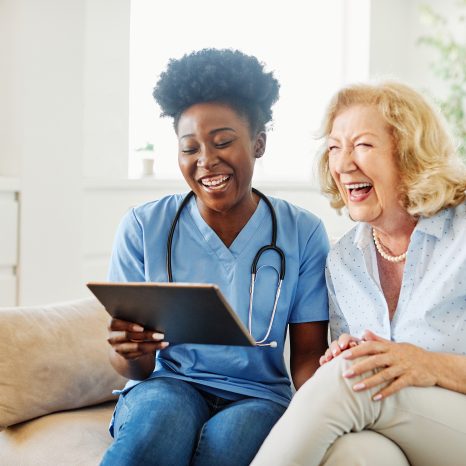 Doctor Or Nurse Caregiver Showing A Tablet Screen To Senior Woma
