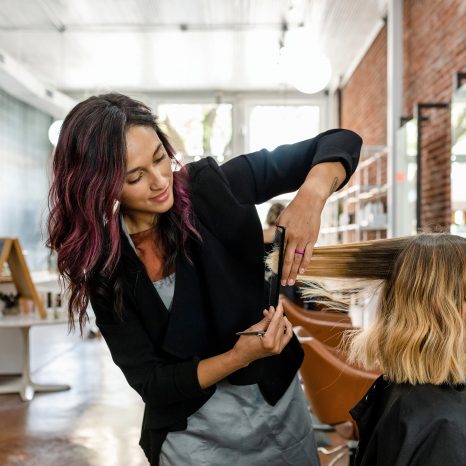 Hairstylist trimming hair of the customer in a beauty salon