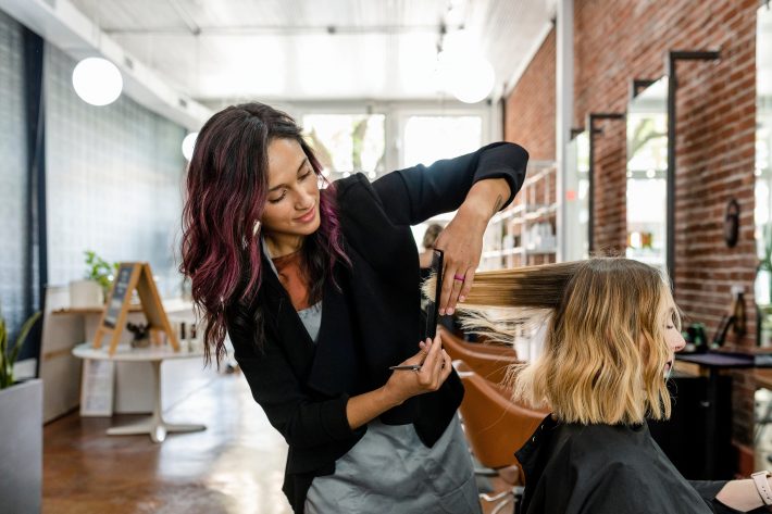 Hairstylist trimming hair of the customer in a beauty salon
