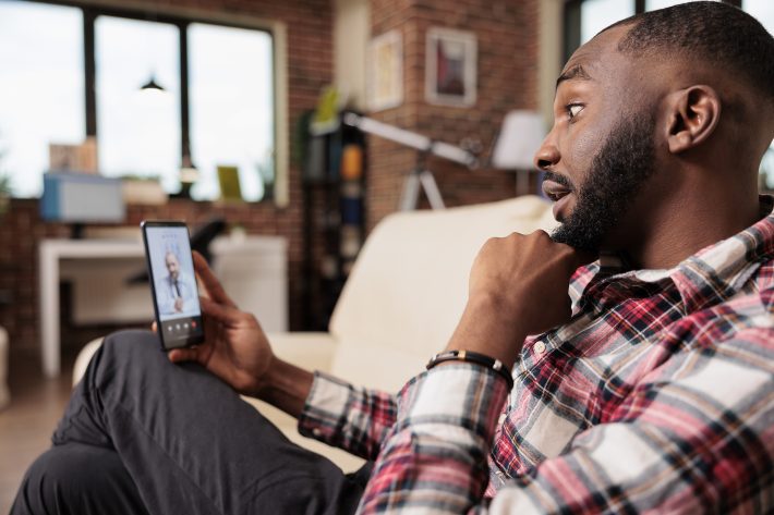 Male Freelancer Talking To Doctor On Videocall With Telehealth O