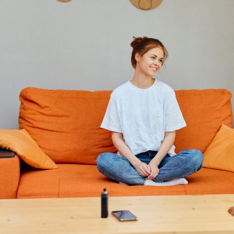Woman At Home On Orange Sofa Phone On Table And Vape