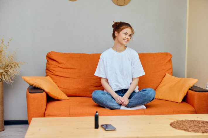 Woman At Home On Orange Sofa Phone On Table And Vape