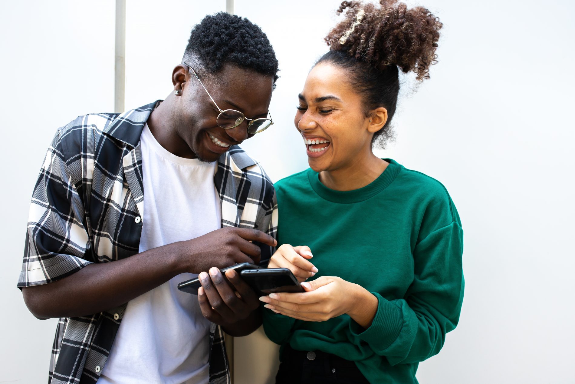 Young African American Couple Laughing Together Using Smart Phon