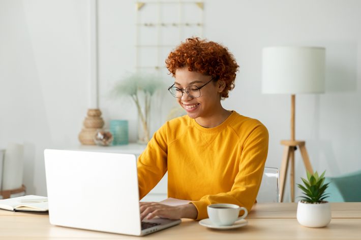 African American Girl Using Laptop At Home Office Looking At Scr