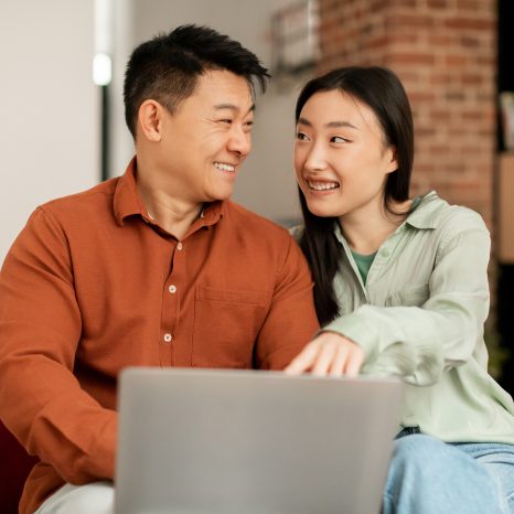Positive Asian Man And Woman Using Laptop, Shopping Online Or Ha