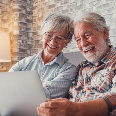 Cute Couple Of Old People Sitting On The Sofa Using Laptop Toget